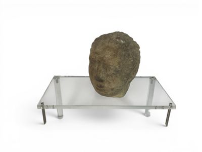 a rock sitting on a glass shelf on a white surface