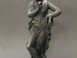 bronze statue of a woman holding a bird on a pedestal