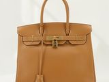 un sac à main en cuir marron muni d'un fermoir doré sur la poignée