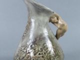 a small vase with a bird on it on a table