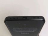 the back of a black cell phone with a small battery on top of it
