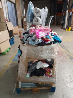 a cart full of clothes in a warehouse with a stuffed animal on top of it