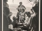 an old black and white photo of a group of people sitting under a tree