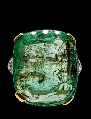 a close up of a ring with a green stone in it