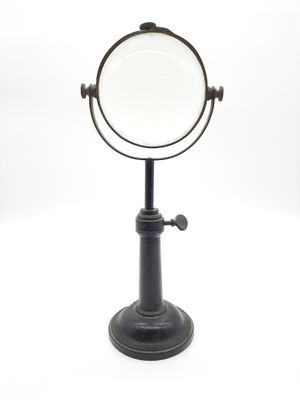 un support noir sur lequel est posé un miroir grossissant
