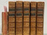 many old books sitting on a shelf next to each other