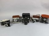 several old cameras are lined up in a row on a white surface