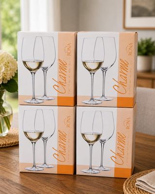 three boxes of wine glasses sitting on a table with flowers in the background