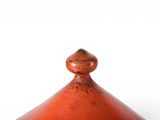 a small red vase with a wooden lid