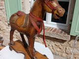 a wooden horse on a table outside of a house