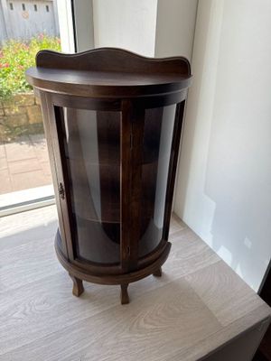 a small wooden cabinet with a glass door on top of a table