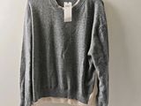 a grey sweater hanging on a hanger against a white wall