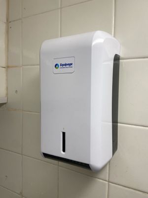 a white paper towel dispenser hanging on the wall