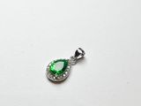 un pendentif vert en forme de larme sur fond blanc