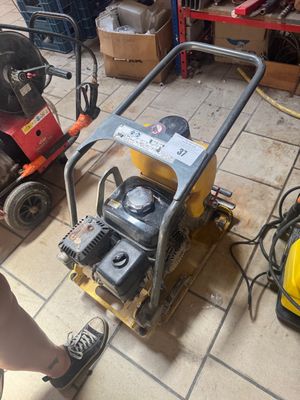 un homme debout à côté d'une petite machine posée au sol