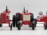 two red tractors sitting side by side on a white surface
