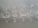 four wine glasses are lined up on a white surface