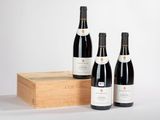 trois bouteilles de vin sont posées à côté d'une caisse en bois