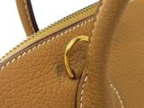 the handle of a tan leather handbag with a gold ring