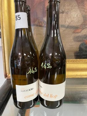 two bottles of wine sitting on a table next to a painting
