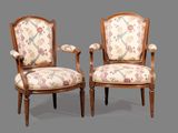 paire de fauteuils de style Louis XVI aux accoudoirs rembourrés d'un motif floral