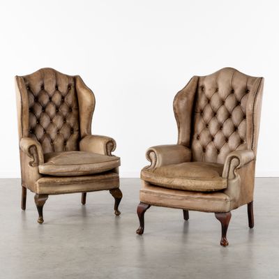 paire de fauteuils à oreilles en cuir avec accoudoirs rembourrés et capitonnés