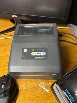 a zebra printer sitting on a desk next to a computer monitor