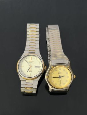 two watches sitting side by side on a black surface