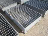 plusieurs grilles en acier sont empilées les unes sur les autres au sol