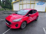La voiture rouge est garée sur le parking situé à l'extérieur du bâtiment.