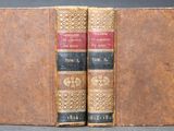two old books sitting on top of each other on a table