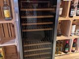 a wine cooler in the middle of a store filled with bottles