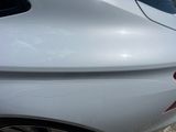 the rear end of a white car with a sticker on it ' s bumper
