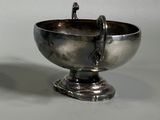 a silver bowl with a handle on a stand