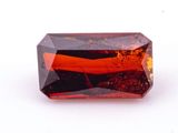 an orange tourmaline gemstone on a white surface