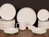 several white plates and cups are stacked on a wooden table
