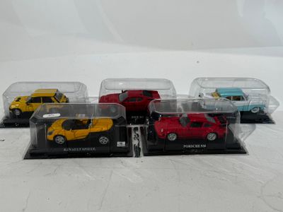four toy cars in a display case on a white surface
