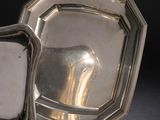 deux assiettes en argent posées sur un support, sur une surface noire