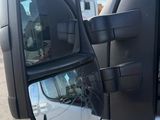 a side view mirror of a truck with a reflection of a building in it