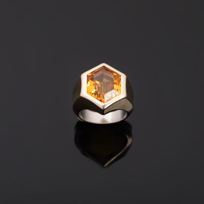 a ring with a faceted citrine stone on a black surface