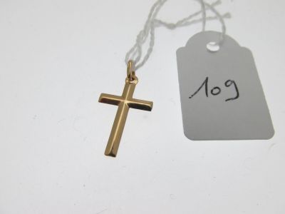une croix en or et une étiquette de prix posées sur une table blanche
