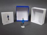 a small figurine of a man standing in front of a box