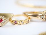 three gold rings with different colored stones on a white surface