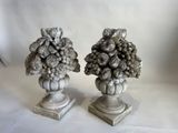 une paire de sculptures représentant des fruits à noyau, posées sur des socles devant un fond blanc