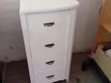 a white chest of drawers next to a bed in a room