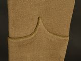 a close up of a tan sweater hanging on a black background