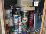 several cans of paint are stacked on top of each other in a shed