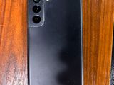 the back of a black samsung phone sitting on top of a wooden table
