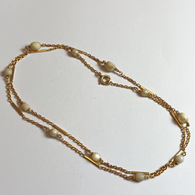 collier avec des perles et une chaîne en or sur fond blanc