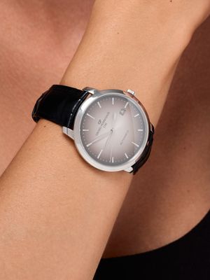 the woman is wearing a black watch with a silver face